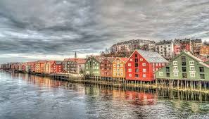 Houses in red and green colors built in a row under dark black clouds. 